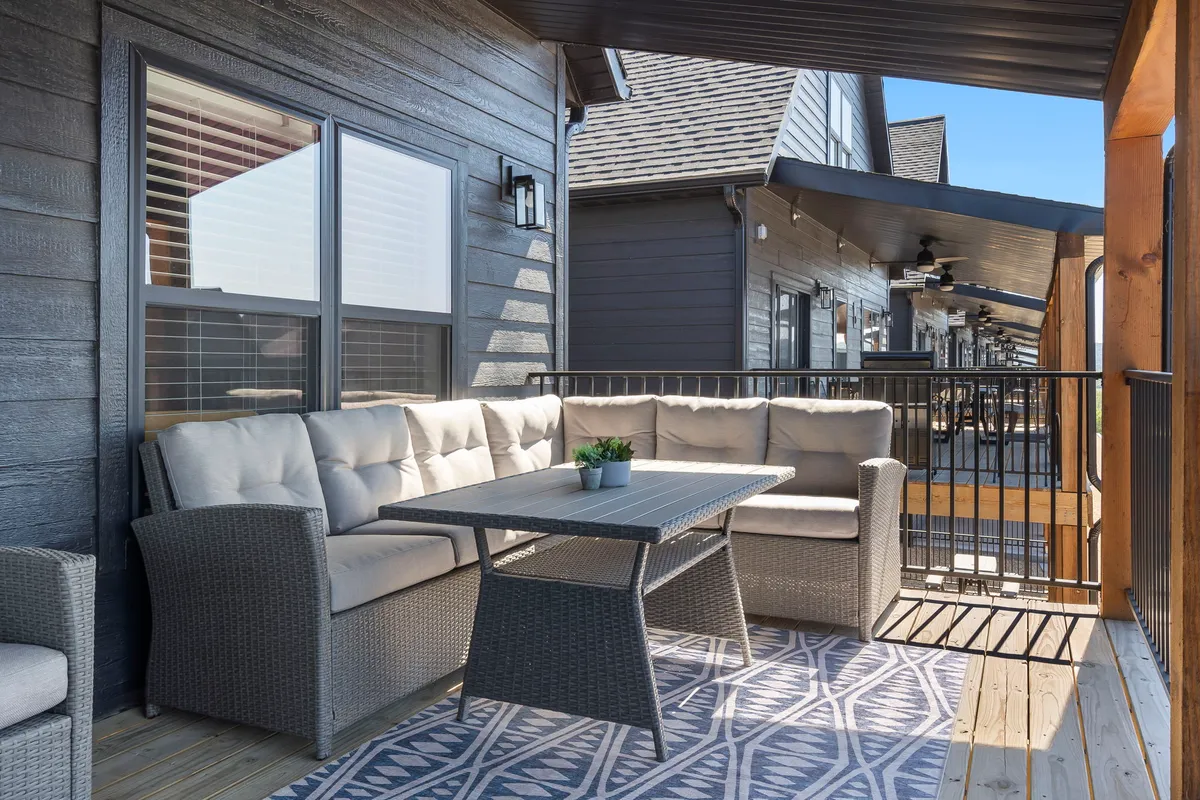 An inviting outdoor seating area with a table adorned by a plant, decorative rug, and comfortable chairs. The setup is ideal for relaxation, socializing, or enjoying a meal while soaking in the view and fresh air.
