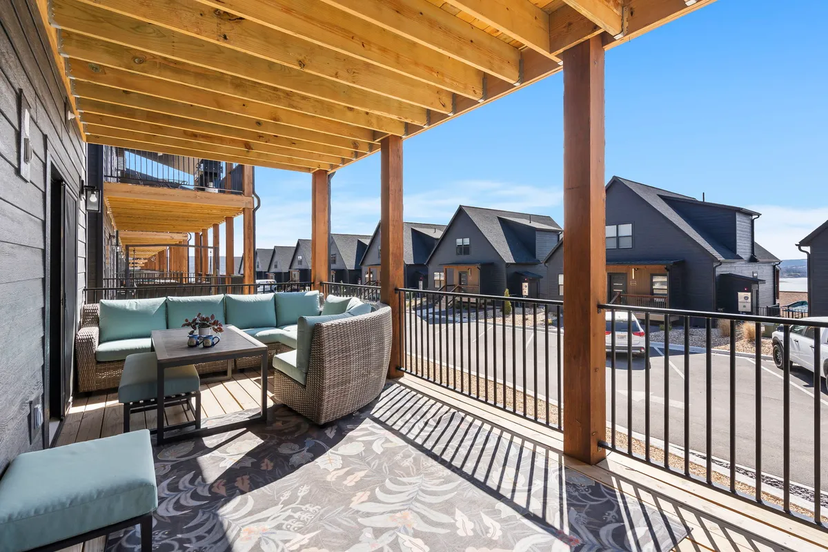 An inviting outdoor seating area with wooden beams, a view of neighboring houses, and decorative flooring. The space is casual and welcoming, suggesting a place for socializing or unwinding after a walk, with plenty of open air for pets to relax beside their owners.