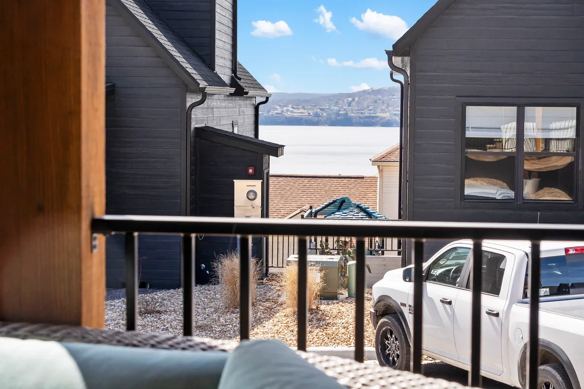 A serene view of the lake framed by surrounding houses and an outdoor area, setting the scene for lakeside relaxation. The composition emphasizes the connection between the property and its beautiful natural environment—perfect for group barbecues or peaceful mornings by the water.