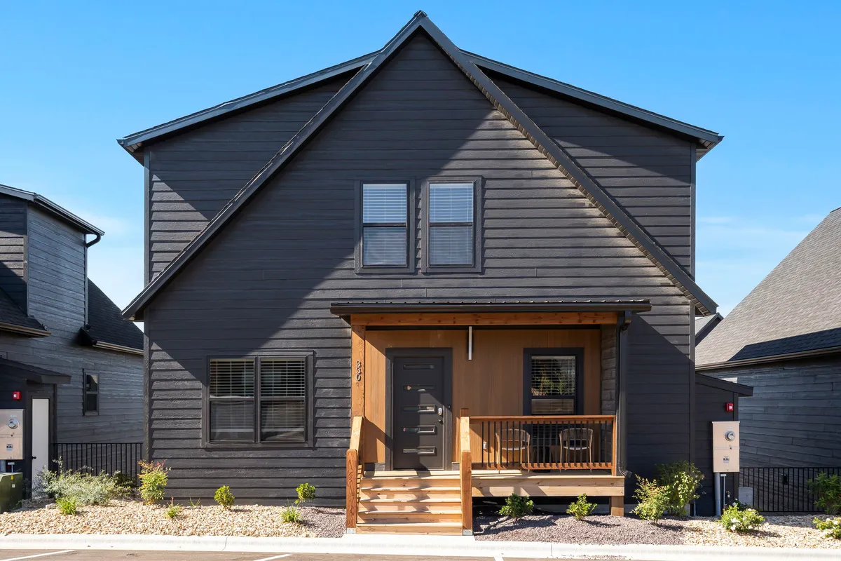 A welcoming front porch with a wooden door and large windows, providing an inviting transition from the indoors to the outdoors. The porch offers a relaxing space that overlooks the natural surroundings, ideal for sitting with your pet and enjoying the Ozark air.